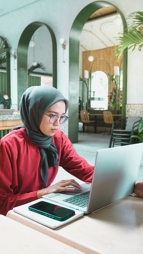Woman Working on a Laptop in a Cafe